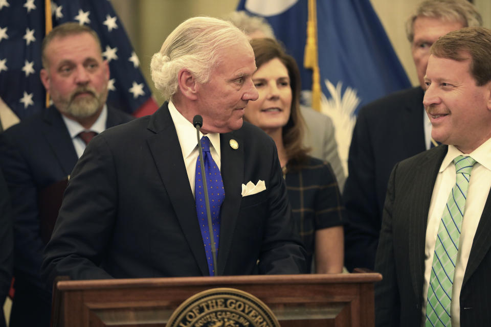 South Carolina Gov. Henry McMaster, left, thanks state Sen. Shane Martin. R-Pauline, right, for his work a bill allowing anyone who can legally own a gun to openly carry the weapon in the state at a event on Tuesday, March 19, 2024, in Columbia, S.C. McMaster signed a ceremonial copy of the bill on March 19 after signing the bill into law March 7. (AP Photo/Jeffrey Collins)