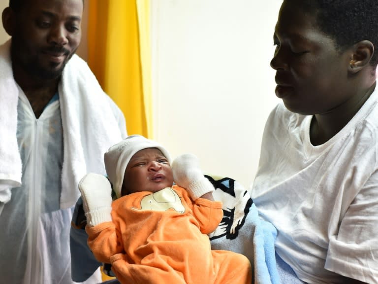 Bernadette Obiona and David Dibonde (L) pose with their newborn Alex aboard the rescue ship "Aquarius", on May 25, 2016, a day after a rescue operation of migrants off the Libyan coast