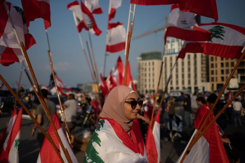 A demonstrator walks past Lebanese national flags during an anti-government protest in downtown Beirut