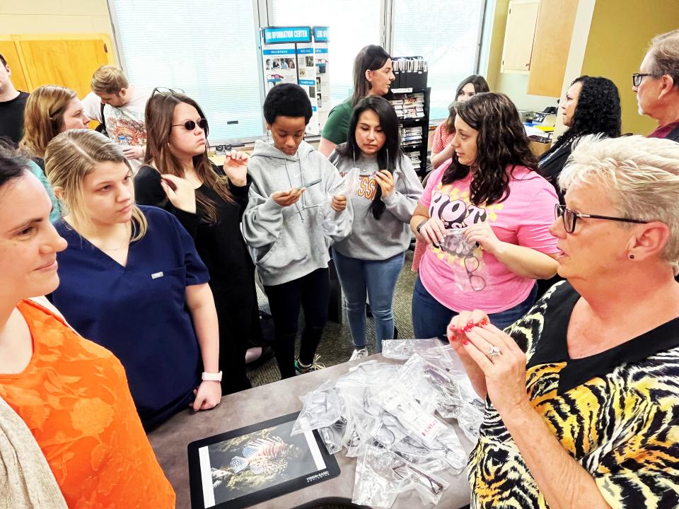 UCOR’s Lisa Russell speaks with students as they examine the safety glasses that UCOR donated