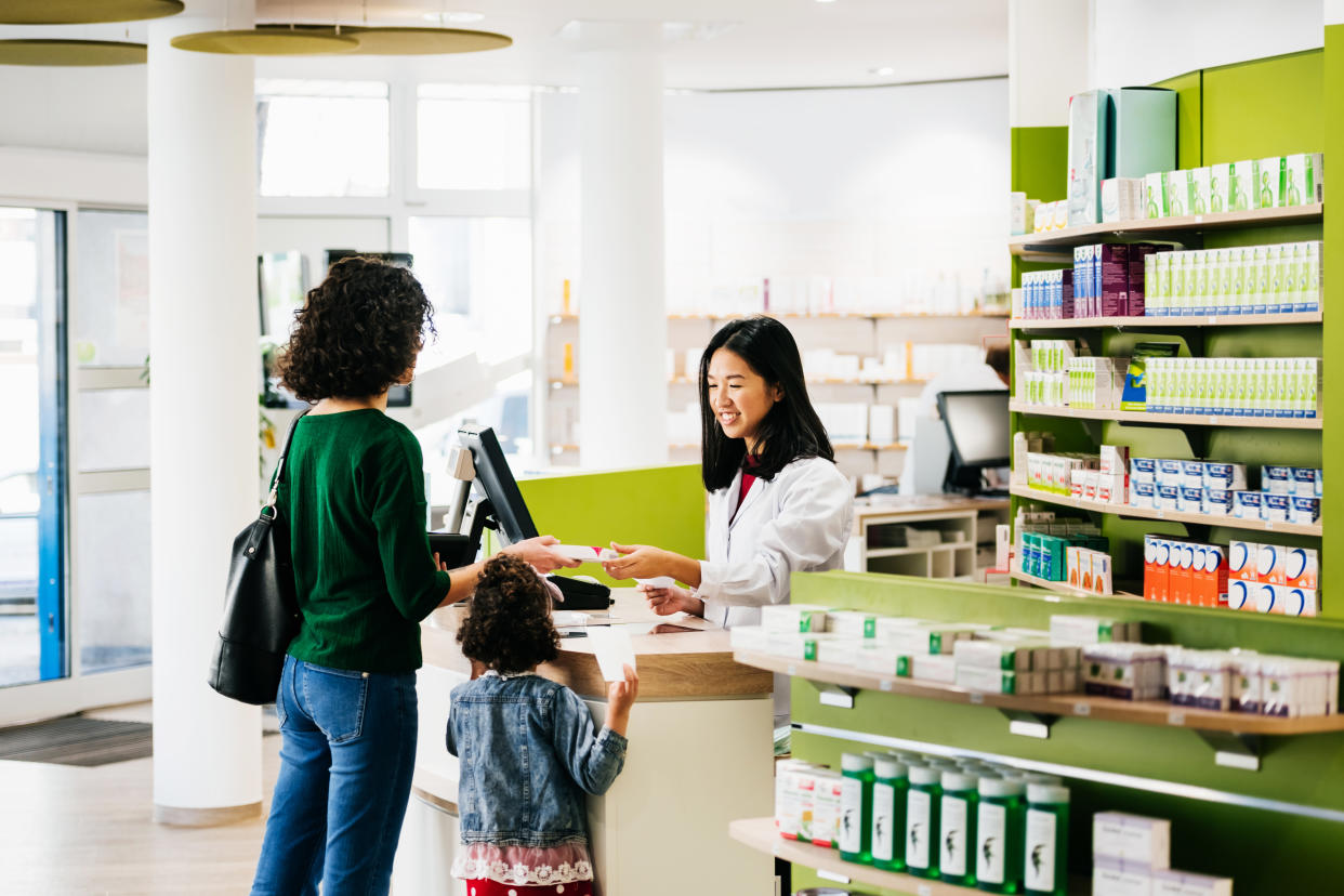 A small family of a mother and young daughter being served their prescriptions a their local pharmacy in the city.