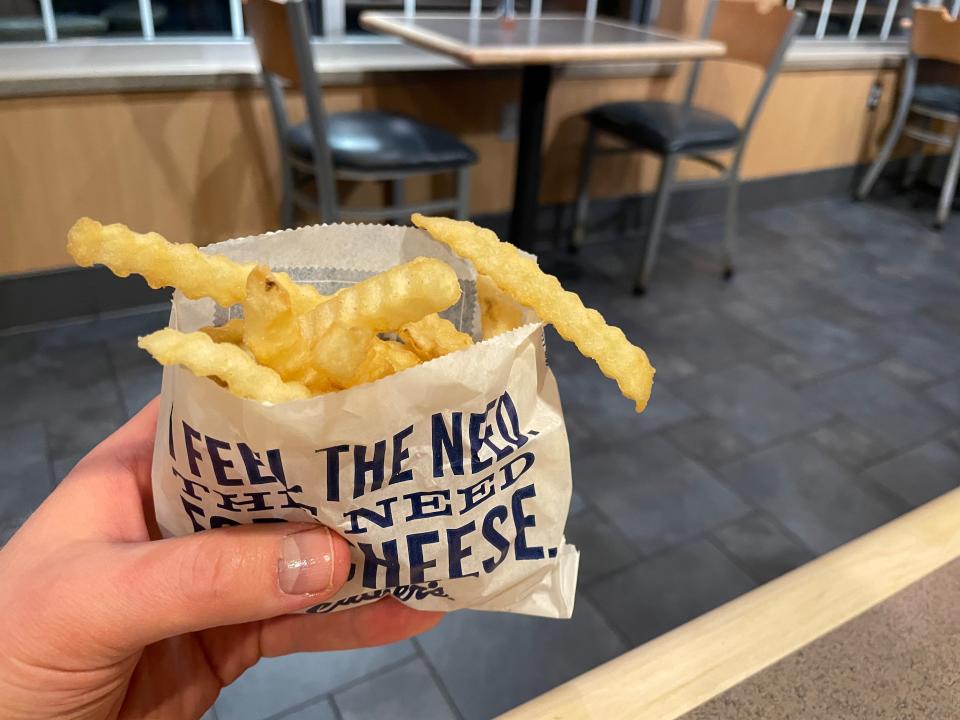 hand holding up a bag of culver's french fries