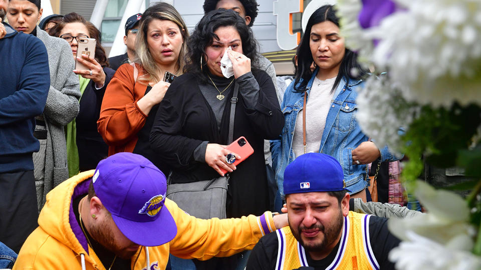 People gather around a makeshift memorial for Kobe Bryant, pictured here at Staples Centre.