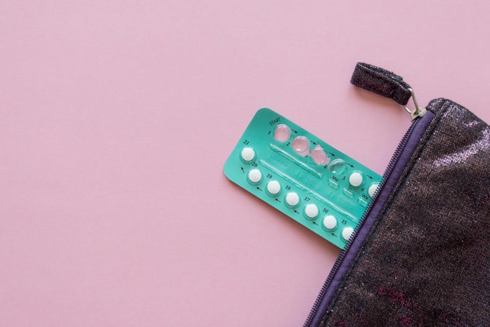 Birth control pills stick out of a zippered pouch