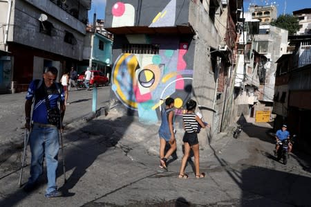 People walk pass a mural painted by Fabian Solymar in Petare slum, in Caracas