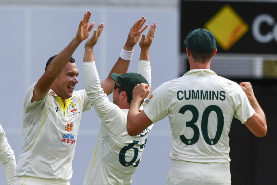 Australia's Scott Boland, left, is congratulated by teammates Travis Head and Pat Cummins, right, after dismissing South Africa's Marco Jansen during day two of the first cricket test between South Africa and Australia at the Gabba in Brisbane, Australia, Sunday, Dec.18, 2022. (AP Photo/Tertius Pickard)