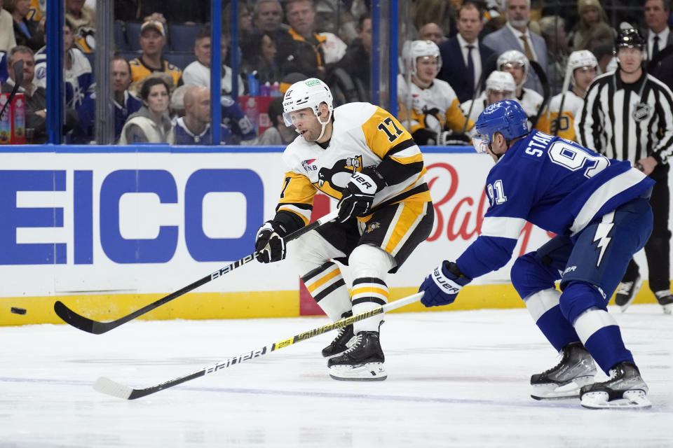 Pittsburgh Penguins right wing Bryan Rust (17) shoots the puck away from Tampa Bay Lightning center Steven Stamkos (91) during the first period of an NHL hockey game Wednesday, Dec. 6, 2023, in Tampa, Fla. (AP Photo/Chris O'Meara)