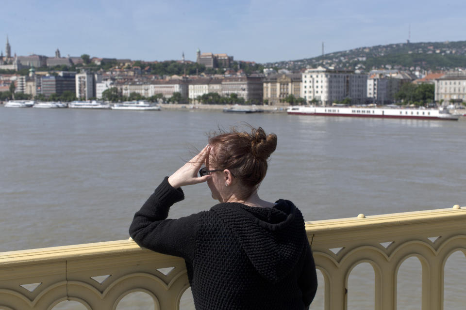 A woman looks out from the Margit bridge as rescue crews work on the Danube river below, as search teams continue to work after a sightseeing boat capsized in Budapest, Hungary, Saturday, June 1, 2019. Hungarian authorities predicted it would take an extended search to find the 21 people still missing after a boat carrying South Korean tourists was rammed Wednesday night by a cruise ship and sank.(AP Photo/Marko Drobnjakovic)