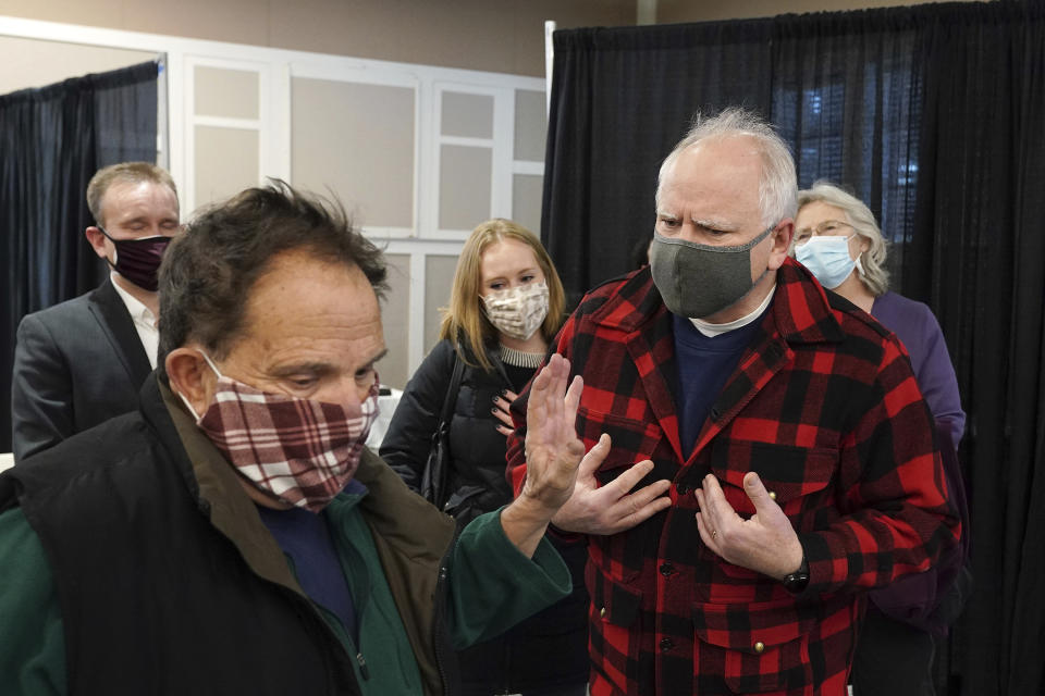 Gov. Tim Walz, right, along with Commissioner for the Minnesota Department of Health Jan Malcolm, rear right, were confronted by a man who opposed their policies as they toured a facility where COVID-19 vaccines were being administered to people with appointments at the Earle Brown Heritage Center, Thursday, Jan. 28, 2021, in Brooklyn Center, Minn. Walz toured a community vaccination clinic to highlight efforts to vaccinate Minnesotans who are 65 and over Thursday. (Anthony Souffle/Star Tribune via AP)
