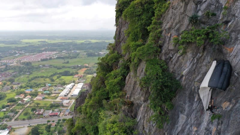 BASE jumper hangs from his parachute at Khao Thalu cliff in Phatthalung