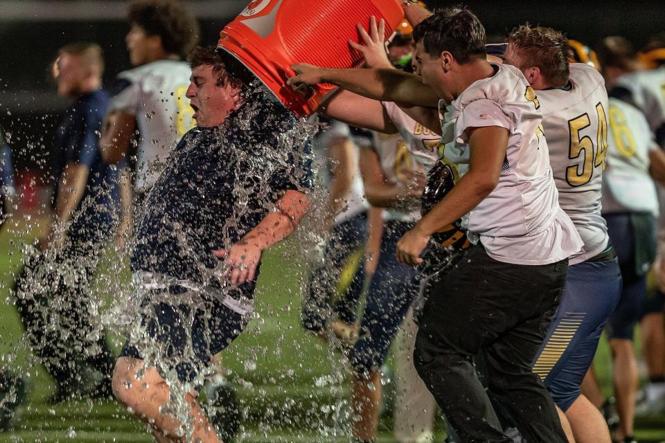 Head football coach Alex Savakinas is doused with iced liquid after the Jupiter Community High School Warriors hosted the Boca Raton Bobcats in a Florida High School Athletic Association boys high school football playoff game at the school in Jupiter, Fla., on November 10, 2023. The Bobcats won 48-41 over the Warriors.