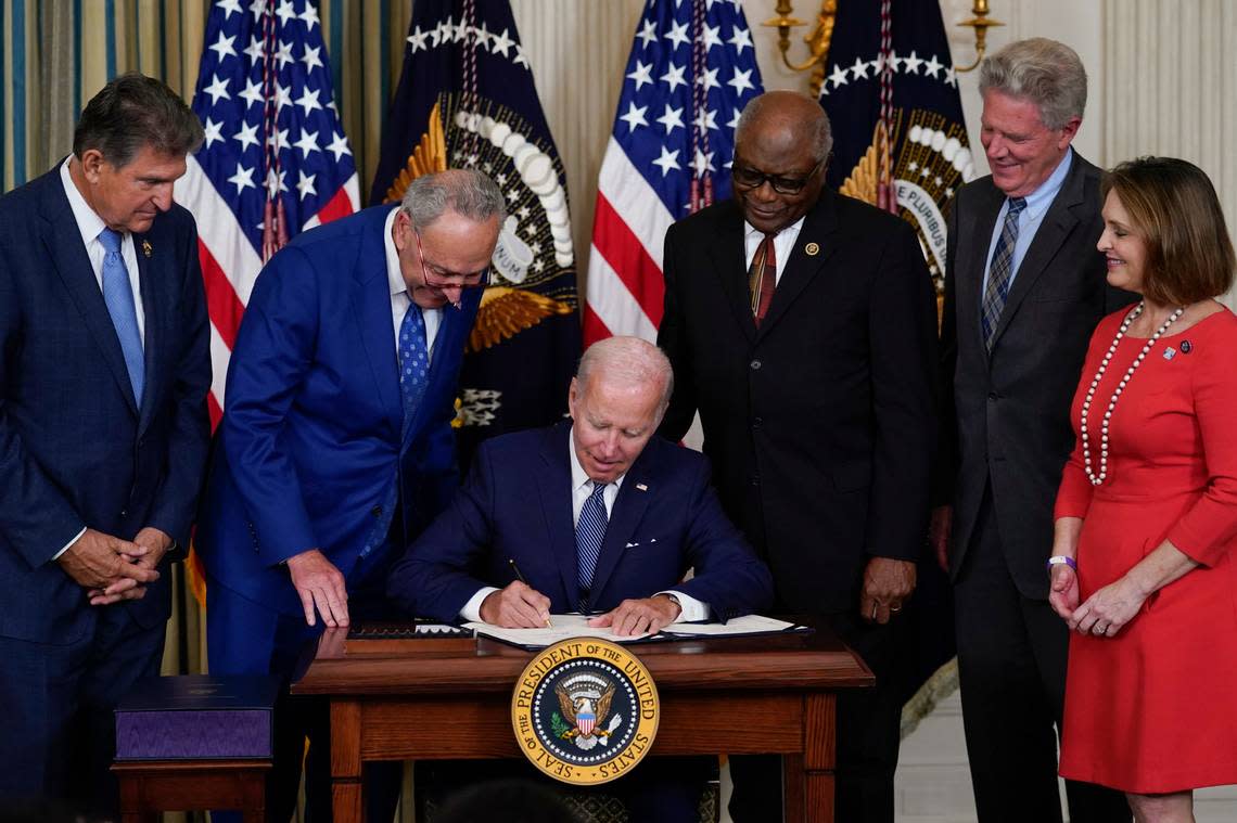 President Joe Biden signs the Democrats’ landmark climate change and health care bill in the State Dining Room of the White House in Washington, Tuesday, Aug. 16, 2022, as from left, Sen. Joe Manchin, D-W.Va., Senate Majority Leader Chuck Schumer of N.Y., House Majority Whip Rep. James Clyburn, D-S.C., Rep. Frank Pallone, D-N.J., and Rep. Kathy Castor, D-Fla., watch. (AP Photo/Susan Walsh)