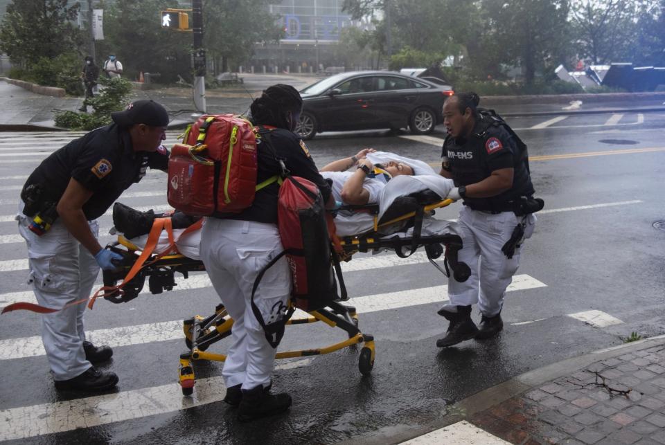 A person who was injured while trying to secure barriers meant to block flood waters at a building at Water and State Streets in lower Manhattan is transported after being injured (AP)