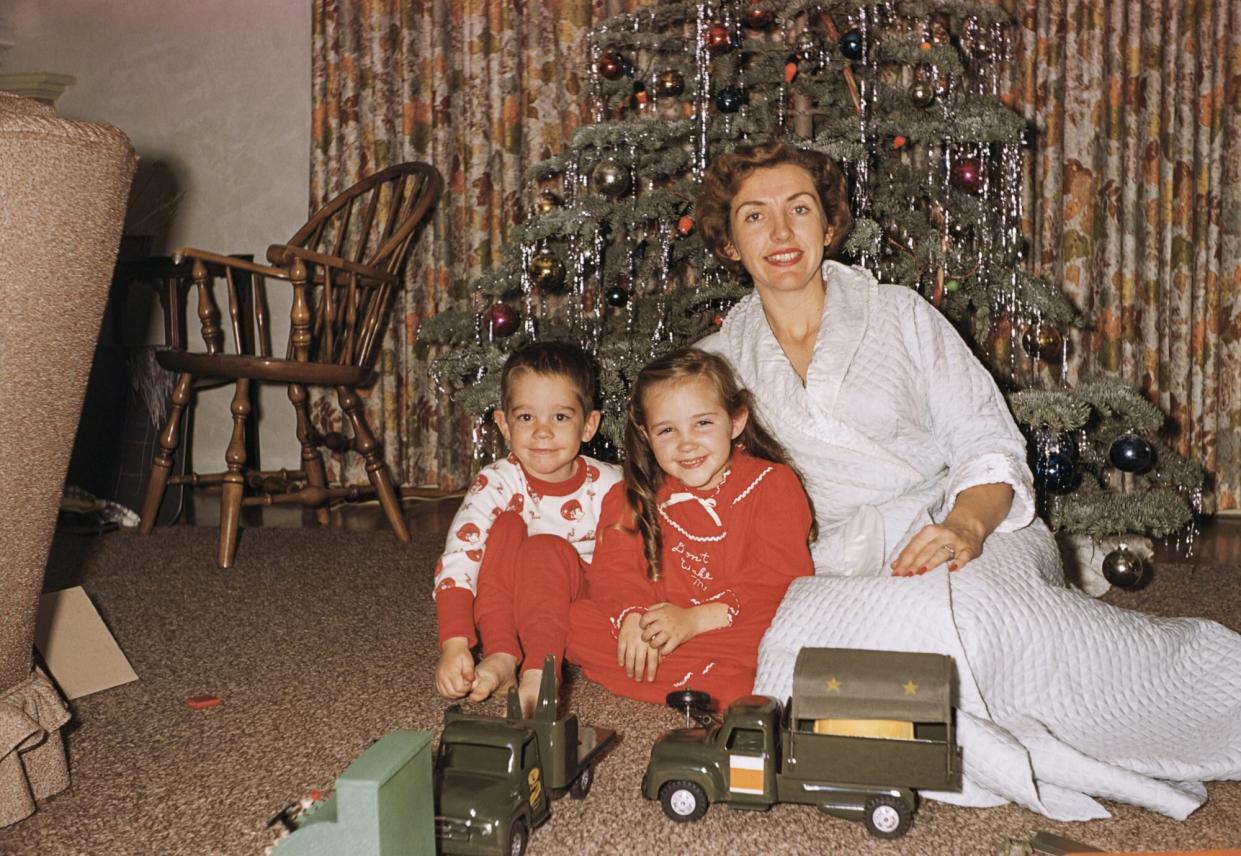 Mother posing with son and daughter near Christmas tree