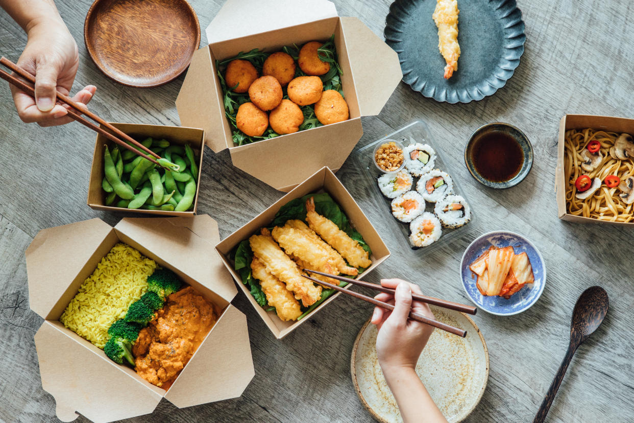 flat lay of takeout meal and people with chopsticks