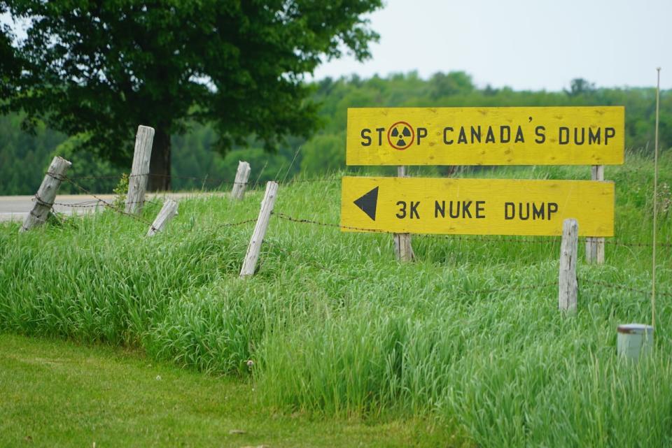 This bright yellow sign, seen here in 2022, was erected by protesters in Teeswater, Ont., a small farming town in the Municipality of South Bruce, one of two sites where the NWMO is considering storing the nation's stockpile of used nuclear fuel.  (Colin Butler/CBC News - image credit)