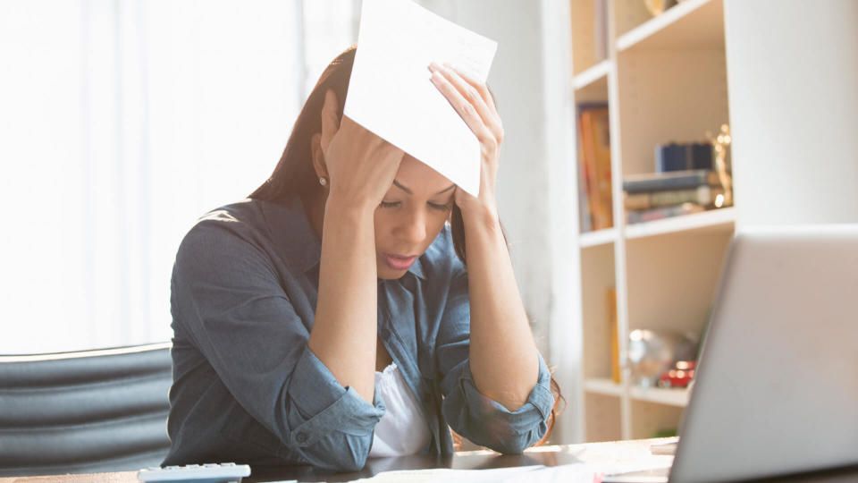 Anxious mixed race woman paying bills on laptop.