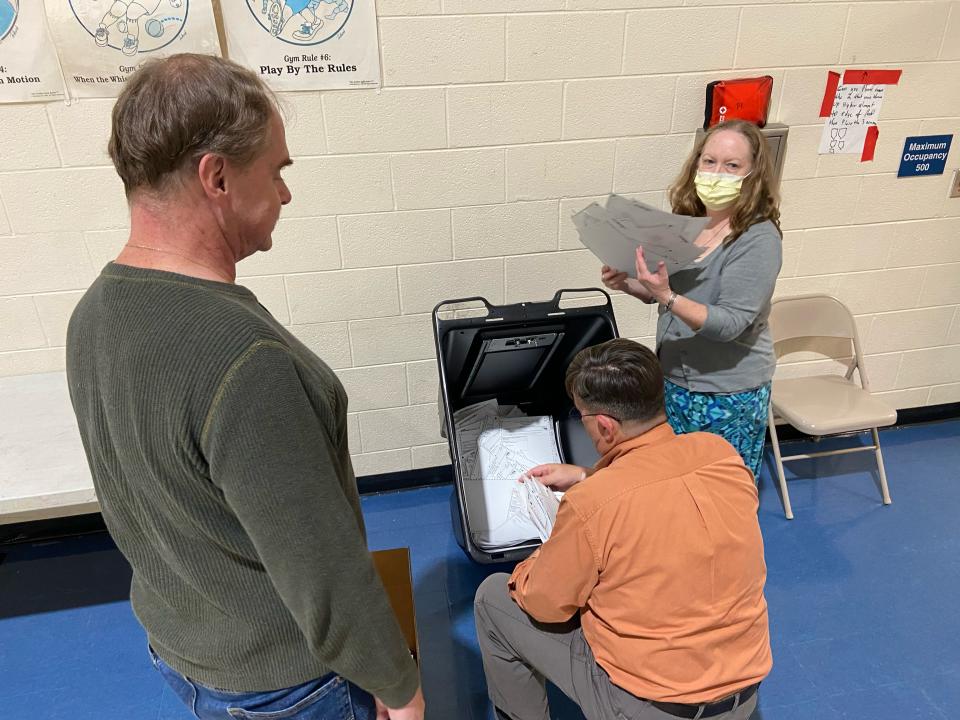 Shelton Mackey, kneeling, polling place supervisor at Salem Elementary School, removed the 863 votes registered there on Nov. 8 from a collection bin for safe storage. Mackey called in the results 10 minutes after polls closed, and only then did he and two other volunteers remove the ballots from a locked bin and place them in a box so they could be stored at the county Board of Elections.