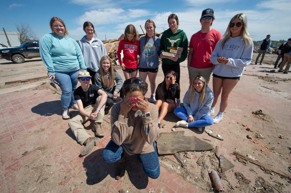 Tracy Harden, center, the owner of Chuck's Dairy Bar in Rolling Fork, Miss., pauses to fight back tears while posing Wednesday, March 29, 2023, on the slab of Chuck's with some of the kids who frequented her restaurant before the EF-4 tornado wiped it out last Friday. "I just love them," Harden said. Instead of being at Chuck's, the students of Sharkey Issaquena Academy were at their prom that night. 