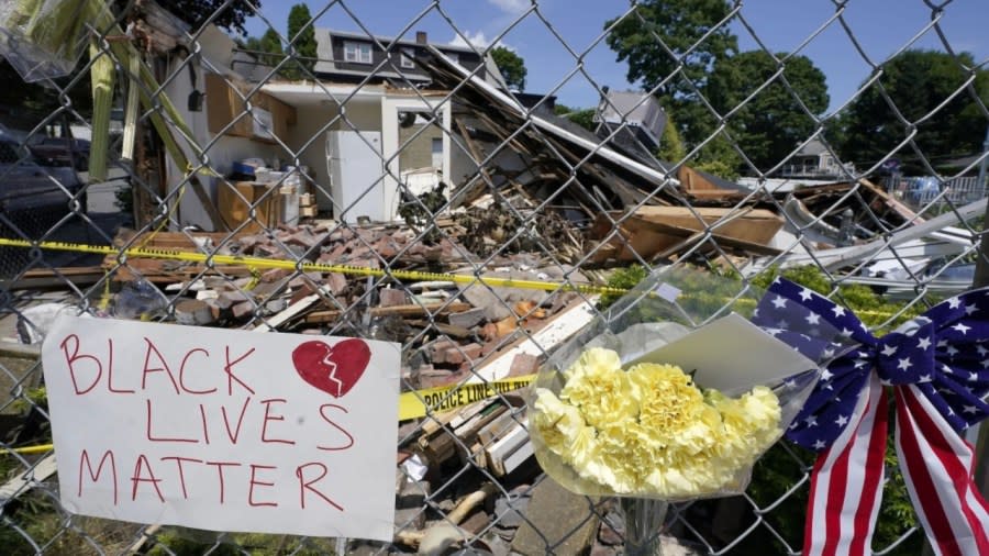 Signs and flowers are attached to a fence outside a building in the Boston suburb of Winthrop, Massachusetts in June 2021, where an armed man crashed a hijacked truck, then fatally shot two Black people before being killed by police. The police officer who fatally shot the man used reasonable force to defend himself and others and won’t face criminal charges, Suffolk District Attorney Kevin Hayden said Tuesday. (Photo: Steven Senne/AP, File)