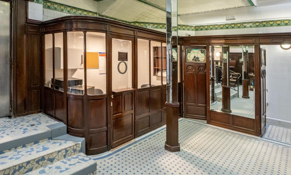 The interior of the restroom, featuring tiles, a reception area, and a large mirror