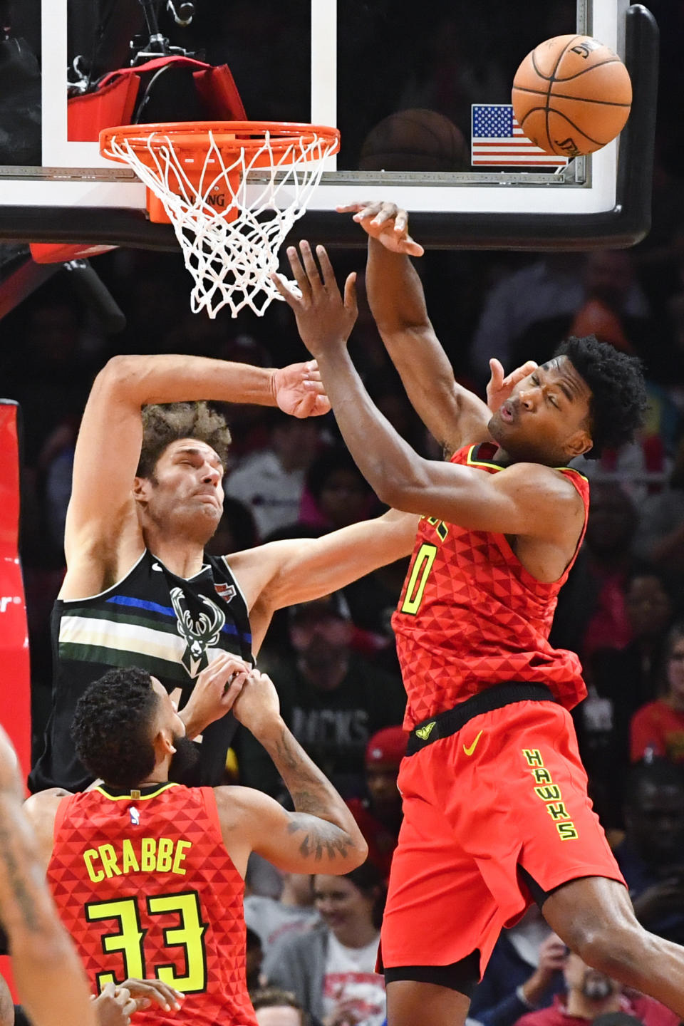 Milwaukee Bucks center Robin Lopez, upper left, and Atlanta Hawks center Damian Jones, right, vie for a rebound as Hawks guard Allen Crabbe (33) looks on during the second half of an NBA basketball game Friday, Dec. 27, 2019, in Atlanta. (AP Photo/John Amis)