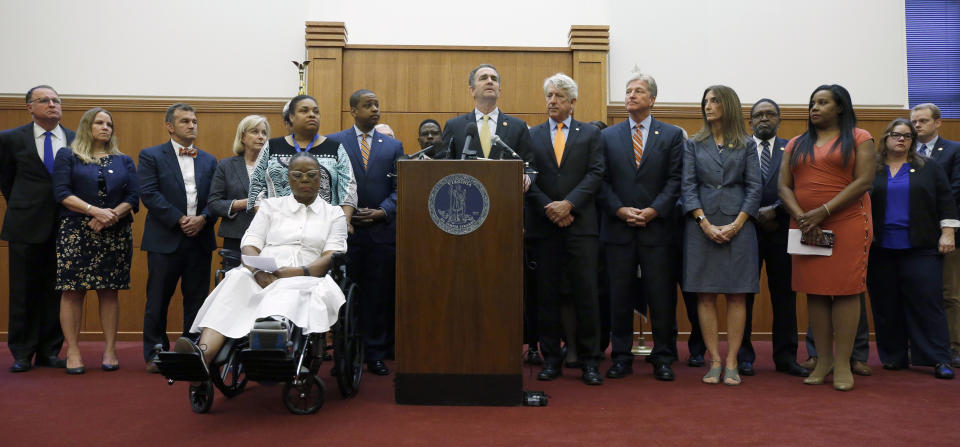 Virginia Governor Ralph Northam, center, pauses while making remarks as he held a press conference dealing with gun violence that was attended by a large number of legislators and activists inside the Patrick Henry Building in Richmond, Va., Tuesday, June 4, 2019. The governor issued an executive order calling for a special session of the legislature later this month to deal with the situation. (Bob Brown/Richmond Times-Dispatch via AP)