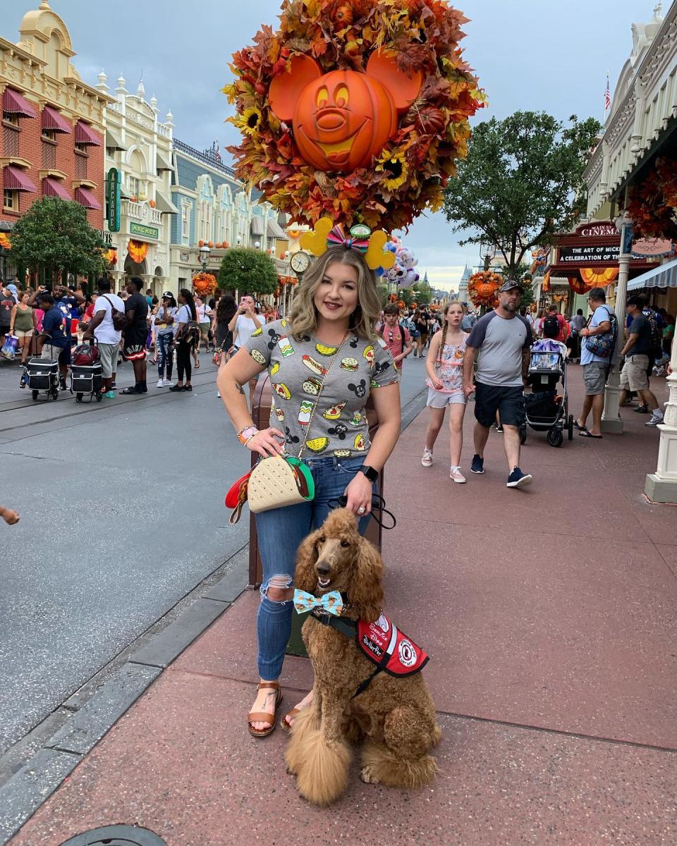 Woman with her service poodle at Disney World. 