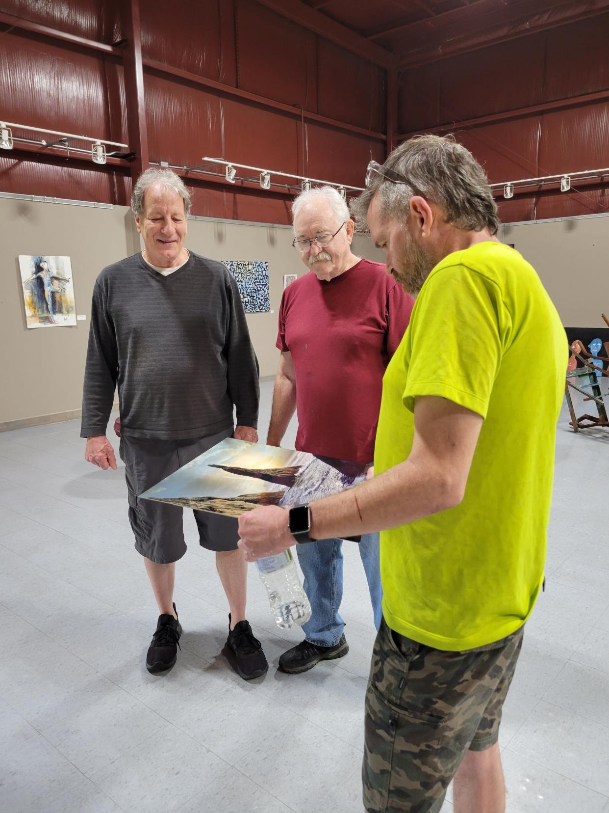 Jon Stucky, left, Bill Koch and Jeff Beitzel check out a photo by Susan Cramer Stein that will be on display during the Mid Summer's Night Art Affair Saturday at the Tuscarawas County Center for the Arts.