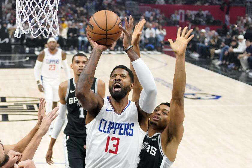 Los Angeles Clippers forward Paul George, center, shoots as San Antonio Spurs.