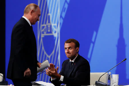 Russian President Vladimir Putin is applauded by his French counterpat Emmanuel Macron after delivering a speech during a session of the St. Petersburg International Economic Forum (SPIEF), Russia May 25, 2018. REUTERS/Grigory Dukor