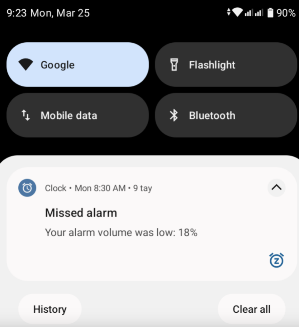 Phone screen showing notification "Your alarm volume was low: 18%" with icons for Google, flashlight, mobile data, and Bluetooth