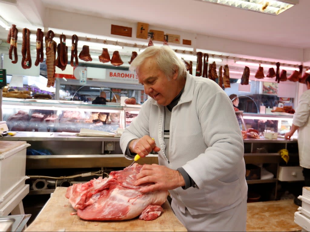 Vendor Misi Kovacs prepers the meat to sell, in a food market in Budapest, Hungary (AP)