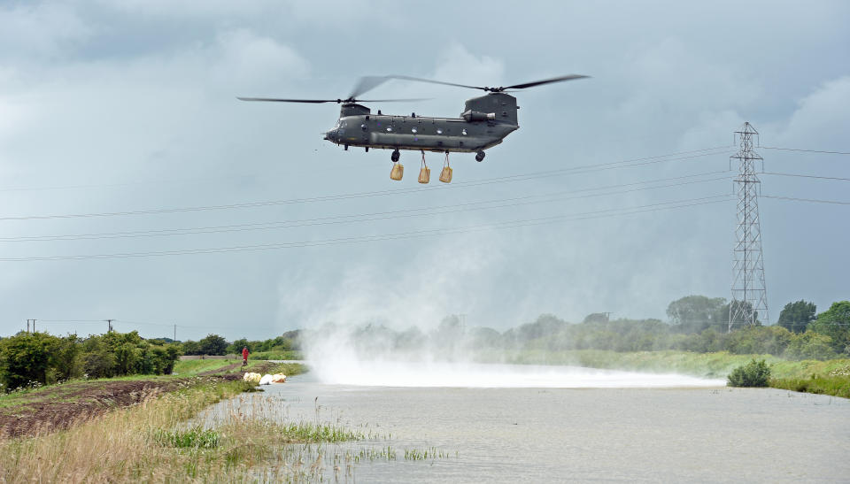 An RAF Chinook helicopter delivers sandbags to plug a gap where the River Steeping burst its banks.