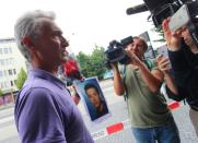 Naim Zabergja speaks with journalists and holds a photo of his son Dijamant who was killed in the attack at the shopping centre in Munich, southern Germany, on July 23, 2016