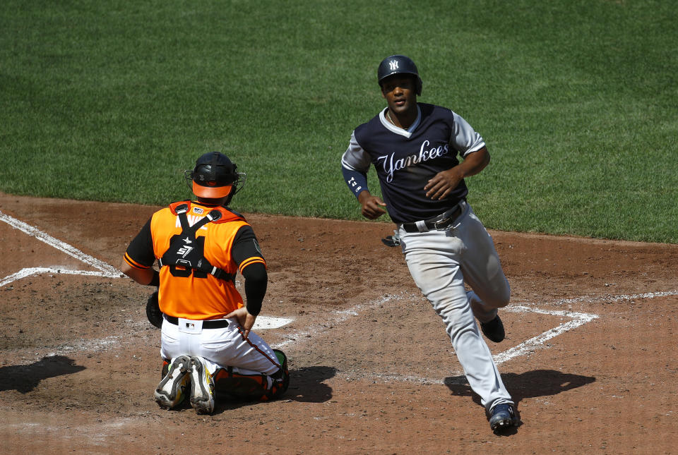 New York Yankees' Miguel Andujar, right, jogs past Baltimore Orioles catcher Austin Wynns after scoring on Luke Voit's single in the fifth inning of a baseball game, Saturday, Aug. 25, 2018, in Baltimore. (AP Photo/Patrick Semansky)