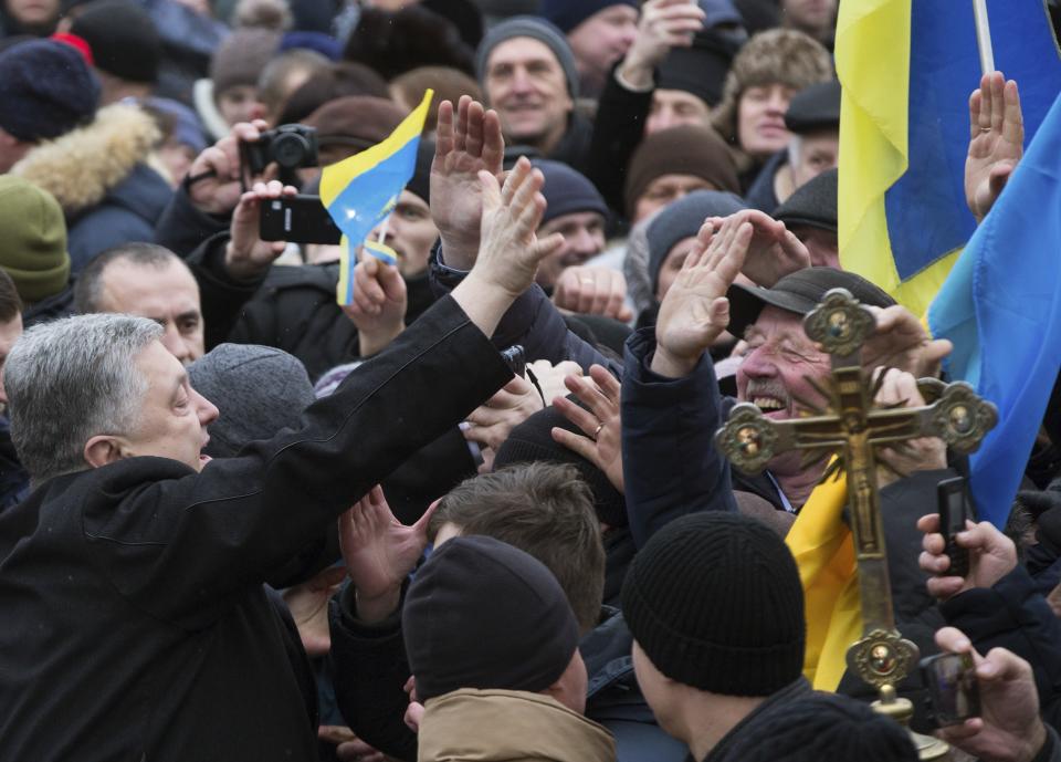 Ukrainian President Petro Poroshenko, left, greets people gathered to support independent Ukrainian church near the St. Sophia Cathedral in Kiev, Ukraine, Saturday, Dec. 15, 2018. Poroshenko has told the crowd "the creation of our Church is another declaration of Ukraine's independence and you are the main participants of this historic event." (Mykhailo Markiv, Ukrainian Presidential Press Service/Pool Photo via AP)