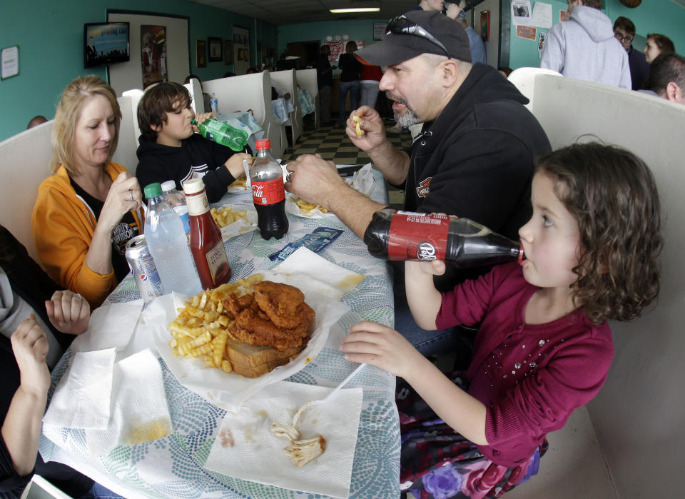 In this Friday, March 23, 2013 photo, Madison Lehman, 5, right, takes a drink after tasting her first piece of hot chicken at Prince's Hot Chicken Shack in Nashville, Tenn. Hot chicken -- fried chicken with varied amounts of seasoning that make the heat level run from mild to extra hot -- is a signature dish of Nashville. Also shown are Cherie Salazar, left, Joey Lehman, 11, and Manny Salazar. (AP Photo/Mark Humphrey)