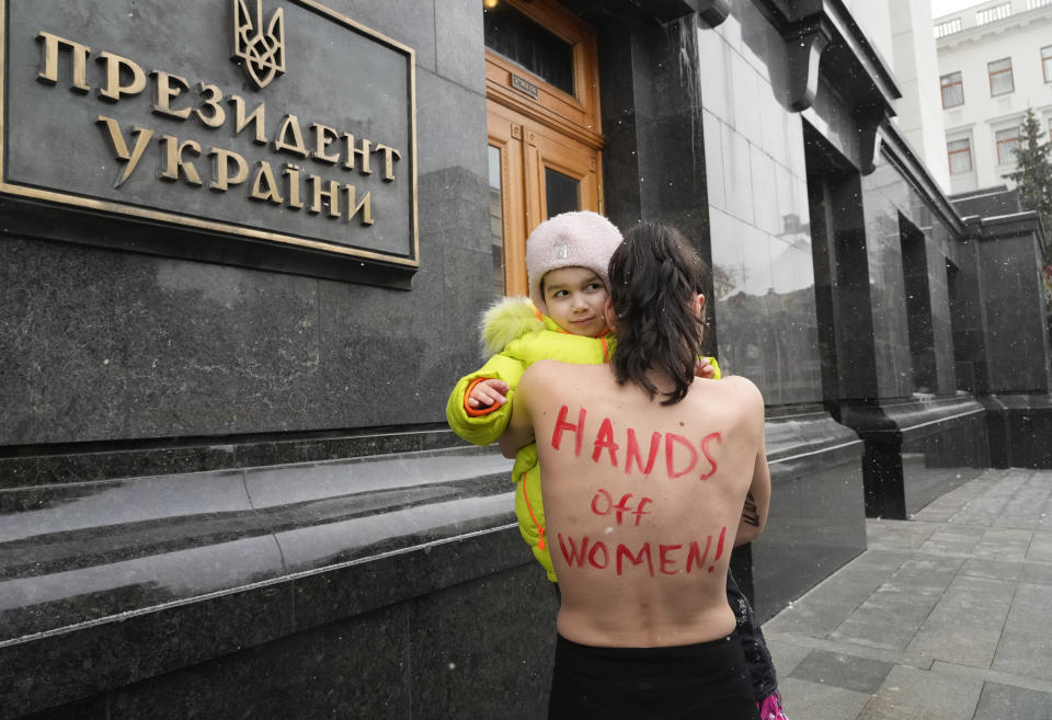 A topless feminist activist from FEMEN protests with her daughter outside Ukraine's President office in Kyiv, Ukraine, Thursday, Jan. 27, 2022, against the government project of military registration for women. (AP Photo/Efrem Lukatsky)