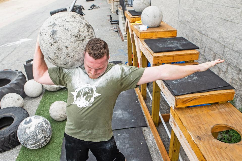 Bradie Crandall carries a 220-pound Atlas stone on his shoulder at the Training Center near New Castle on Thursday, Aug. 3, 2023. Crandall, a chemical engineering doctoral candidate at the University of Delaware, is among the nation's top powerlifters and a vegan.