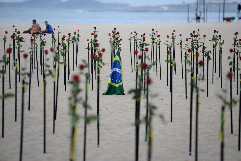 A Brazilian national flag is seen amidst red flowers placed by Rio de Paz NGO on Copacabana beach to pay tribute to the Brazil's half a million COVID-19 deaths in Rio de Janeiro, Brazil, June 20, 2021. REUTERS/Lucas Landau