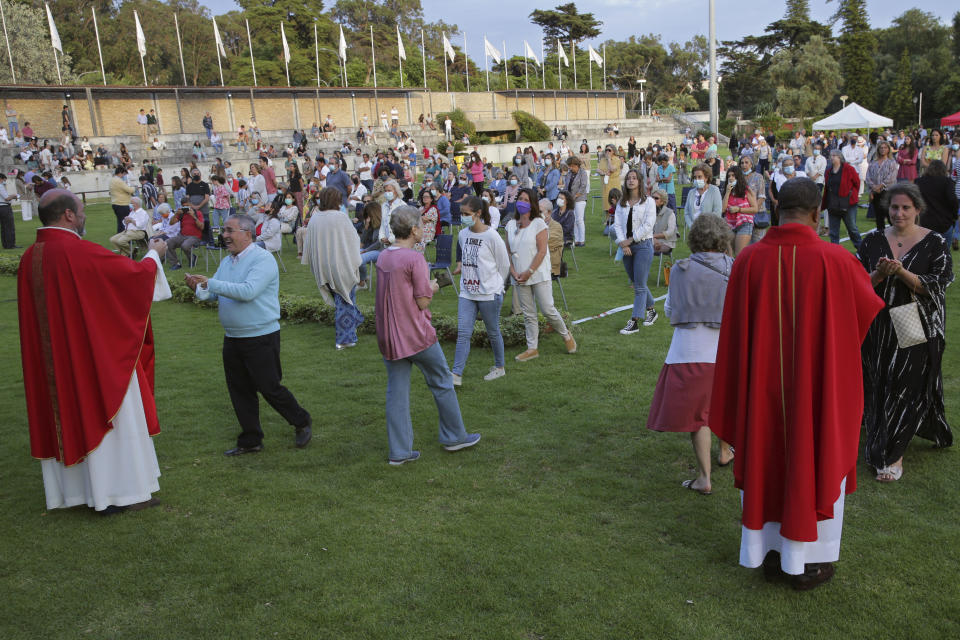 Worshippers queue to receive the communion wafer during an outdoor mass at the hippodrome in Cascais, outside Lisbon, Sunday, May 31, 2020. As the government eases the coronavirus lockdown rules, the Catholic Church in Portugal resumed the celebration of religious services Saturday with a set of safety rules to avoid the spread of COVID-19. (AP Photo/Armando Franca)