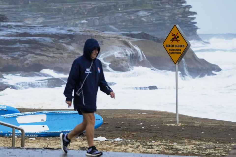 A man walks along the beach front at Bronte Beach as rain continues to fall in Sydney, Australia, Wednesday, July 6, 2022. More than 50,000 residents of Sydney and its surrounds have been told to evacuate or prepare to abandon their homes on Tuesday as Australia's largest city braces for what could be its worst flooding in 18 months. (AP Photo/Mark Baker)