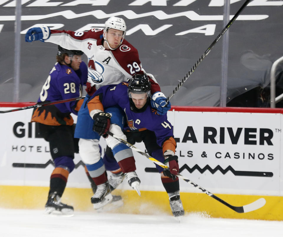 Colorado Avalanche's Nathan MacKinnon gets sandwiched between Arizona Coyotes' Dryden Hunt, right, and Niklas Hjalmarsson during the first period of an NHL hockey game Saturday, Feb. 27, 2021, in Glendale, Ariz. (AP Photo/Darryl Webb)