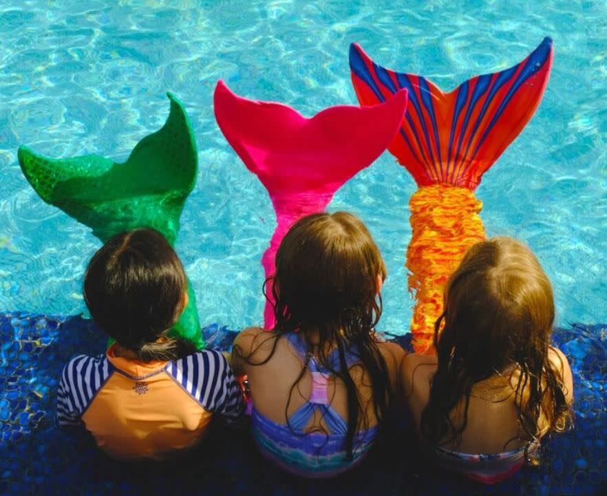 three kids at the pool wearing mermaid tails at the hyatt regency maui, a good housekeeping pick for best family vacation destinations