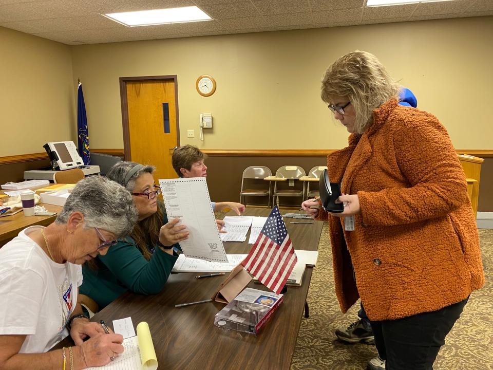 Election worker Tammy Harry, center left, gave a ballot to Sherri Kauffman about 20 minutes after the poll opened at 7 a.m. Nov. 7 at the Peters Township municipal building in Lemasters. Also pictured are Harry’s fellow poll workers Lisa Mellott, far left, and Sherrie Mellott.