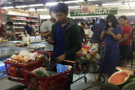 People line up to buy food and other supplies at a 24-hour supermarket in Yangon, Myanmar, Tuesday, March 24, 2020, following the first cases of coronavirus announcement. Myanmar has announced its first two confirmed cases of COVID-19, one in the nation's biggest city, Yangon, and the other in the western state of Chin. For most people, the new coronavirus causes only mild or moderate symptoms. For some it can cause more severe illness. (AP Photo/Thein Zaw)