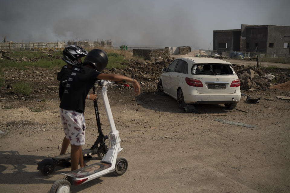 Boys look at a damaged car after shelling fired from Lebanon in Katsrin, a city near the border with Lebanon, northern Israel, Thursday, June 13, 2024. (AP Photo/Leo Correa, File)