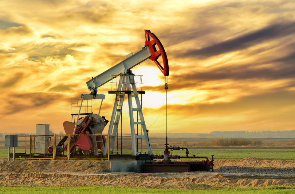 Crude oil pump jack at oilfield on sunset backround. Fossil crude output and fuels oil production. Oil drill rig. Crude mining concept. Oil prices on the trading exchange.