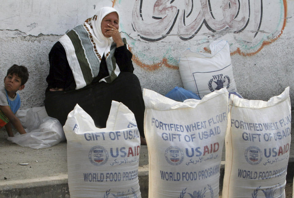 A Palestinian woman sits next to sacks of flour outside the UN Relief and Works Agency, (UNRWA) aid distribution station in Gaza City, June 20, 2007. (AP Photo/Khalil Hamra, file)